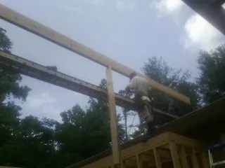 Carpenter setting a ridge beam over a new addition frame — Ice Dam Removal by Roofing Brothers in Lometa