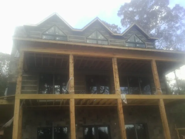 Dormers and porch framing on a large log home under construction — Roof Coating work by our crew in Lometa
