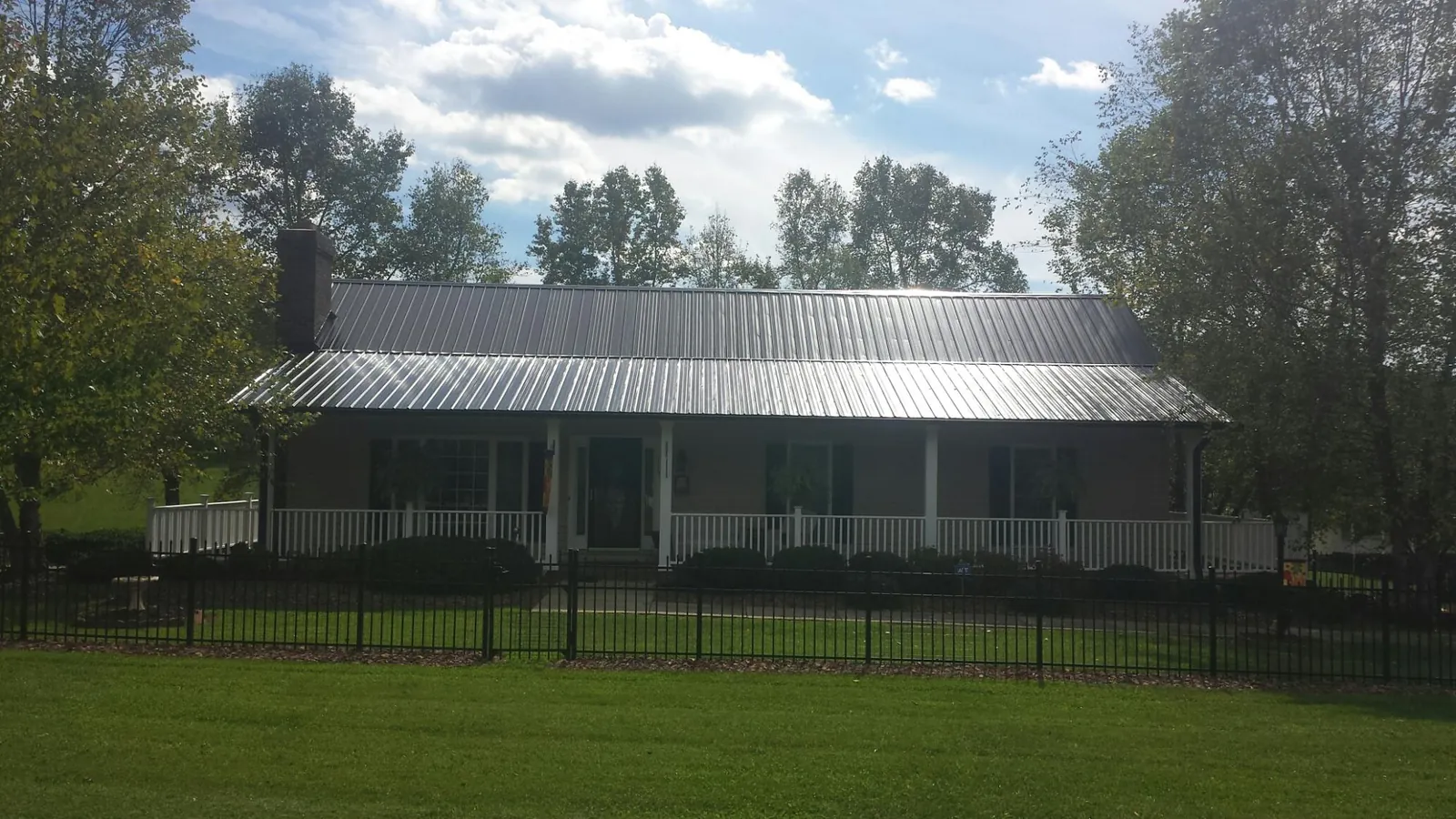 Gray metal roof on a brick ranch with a full width front porch — Gutter Guard Installation work by our crew in Lometa